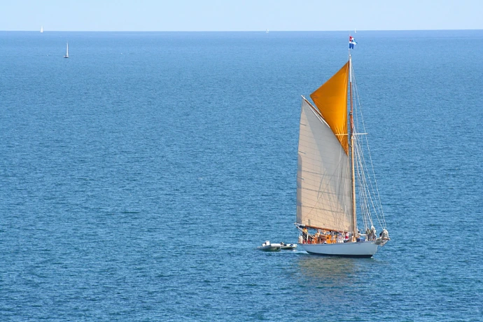 Sailboat with colorful sails glides across the ocean.
